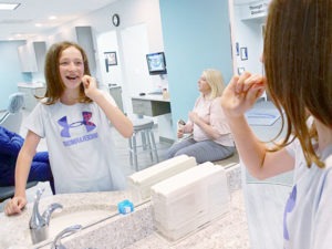 Girl brushing teeth in mirror