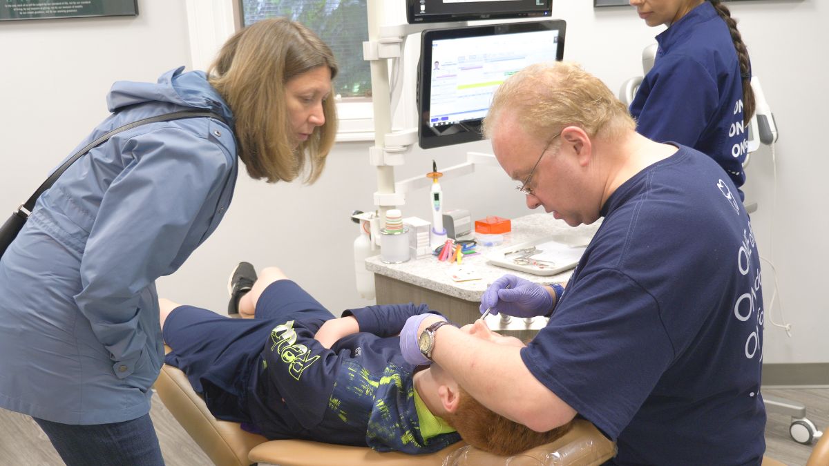 Dr. Demas working on a young patient while showing the patient's mom.